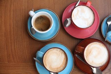 Cups of fresh aromatic coffee on wooden table, top view