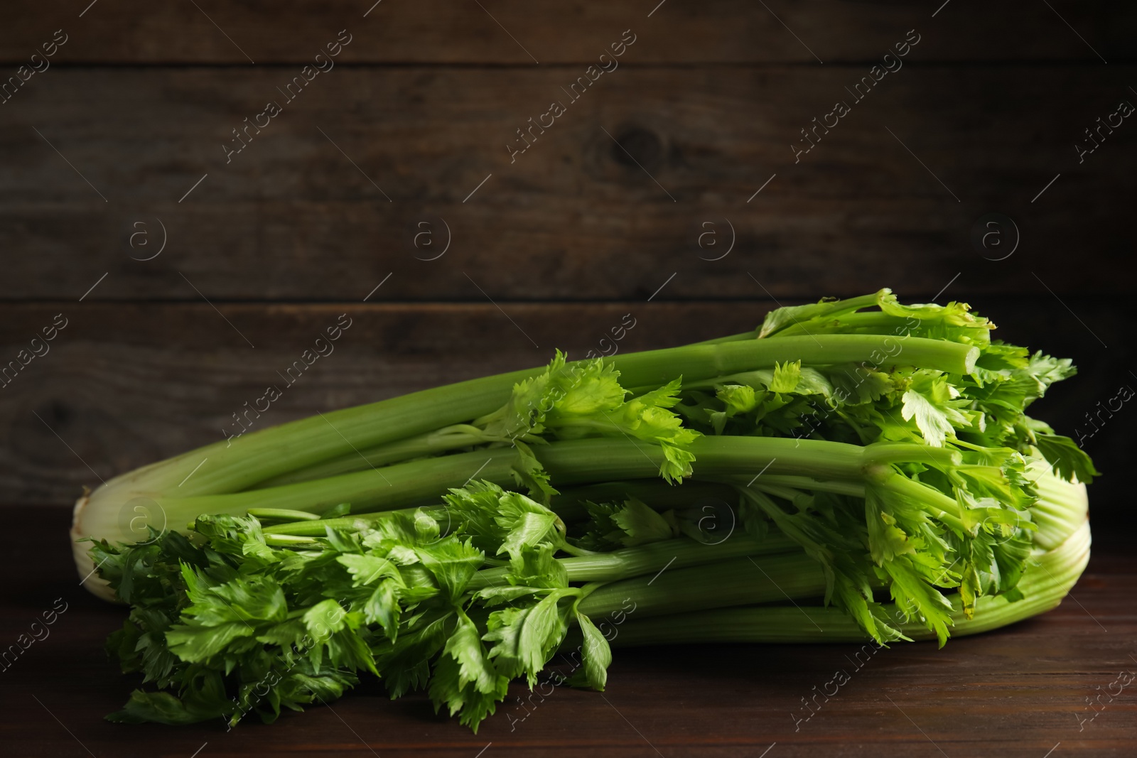 Photo of Fresh ripe green celery on wooden table. Space for text