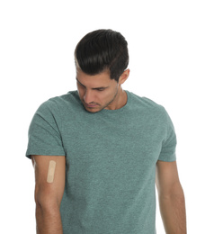 Man with sticking plaster on arm against white background