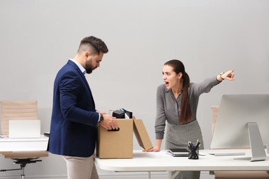 Boss dismissing young man from work in office