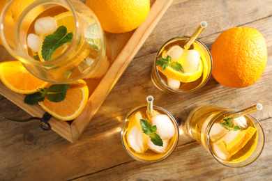 Delicious refreshing drink with orange slices on wooden table, flat lay
