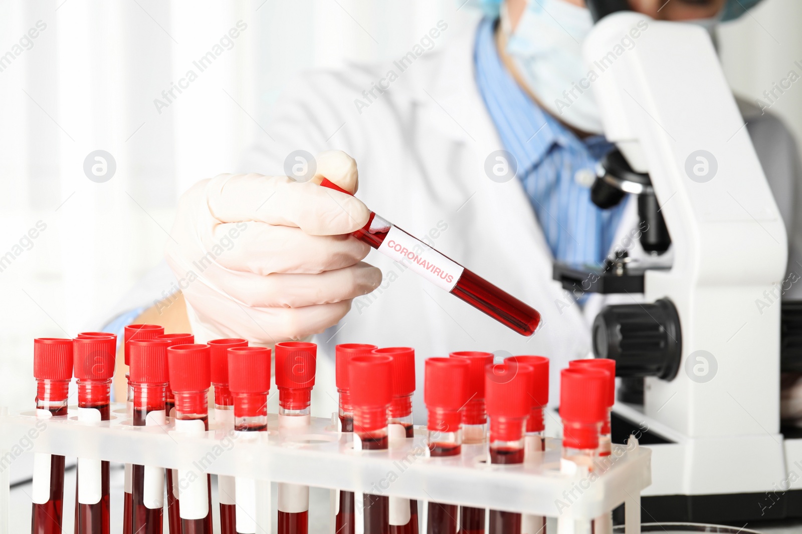 Photo of Scientist holding test tube with blood sample and label CORONA VIRUS in laboratory, closeup