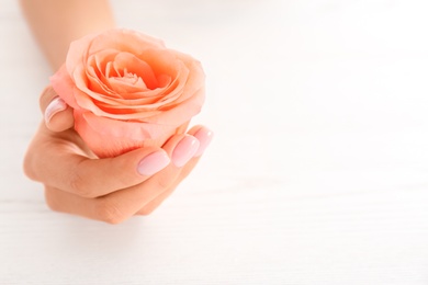 Photo of Closeup view of woman with rose at white table, space for text. Spa treatment