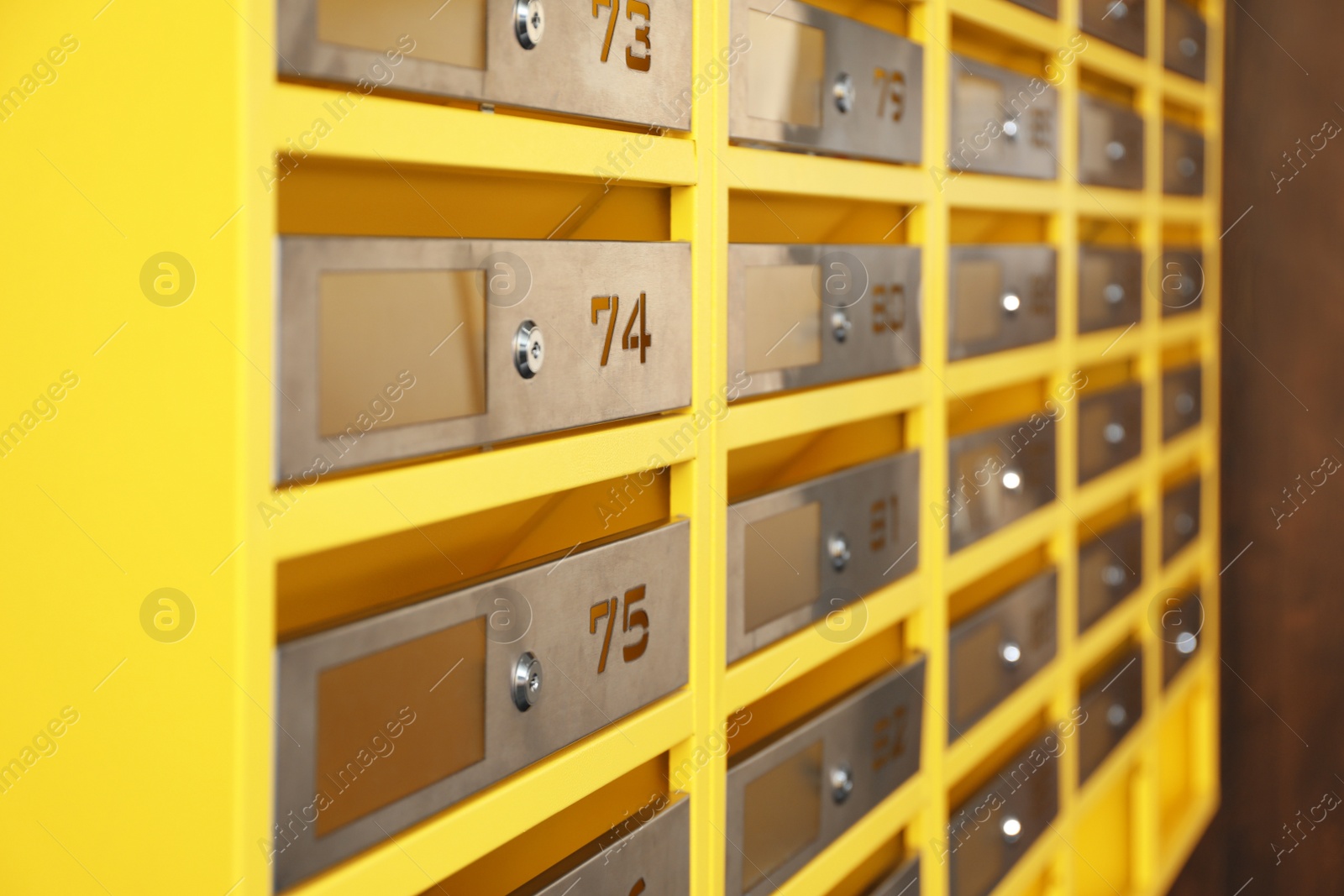 Photo of Many closed metal mailboxes with keyholes and numbers in post office, closeup