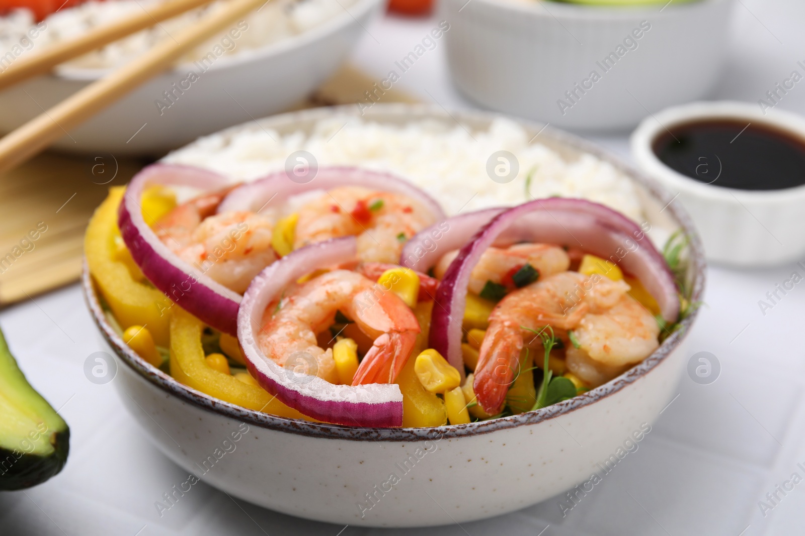 Photo of Delicious poke bowl with shrimps, rice and vegetables on white table, closeup