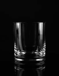 Photo of New empty whiskey glass on black background