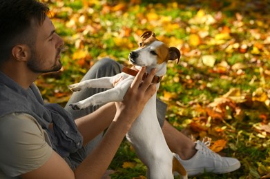 Photo of Man with adorable Jack Russell Terrier in autumn park. Dog walking