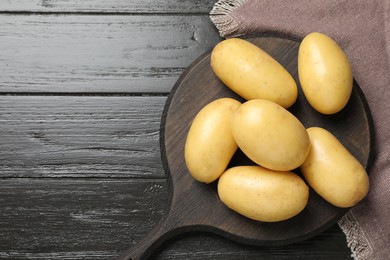 Photo of Fresh raw potatoes on wooden table, top view. Space for text