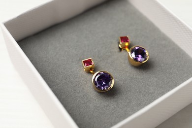 Earrings in jewel box on white table, closeup