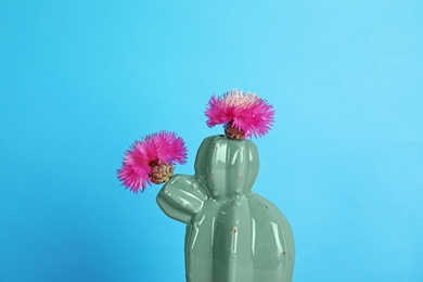 Photo of Trendy cactus shaped ceramic vase with flowers on color background