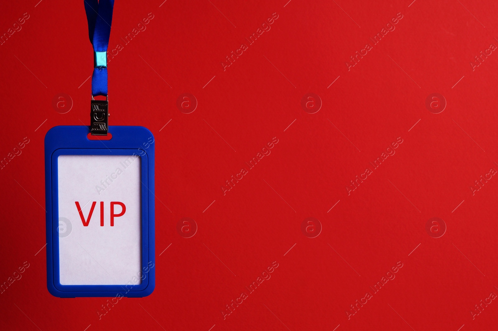 Photo of Blue plastic vip badge hanging on red background, space for text