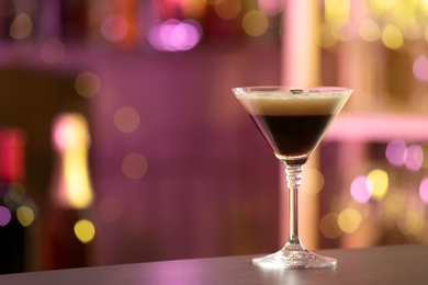 Photo of Glass of Espresso Martini on counter in bar, space for text. Alcohol cocktail