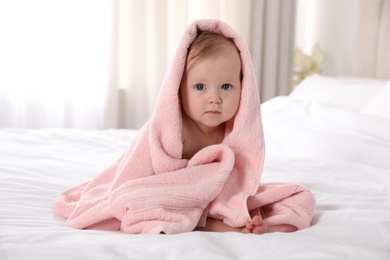 Photo of Cute little baby with soft pink towel on bed after bath