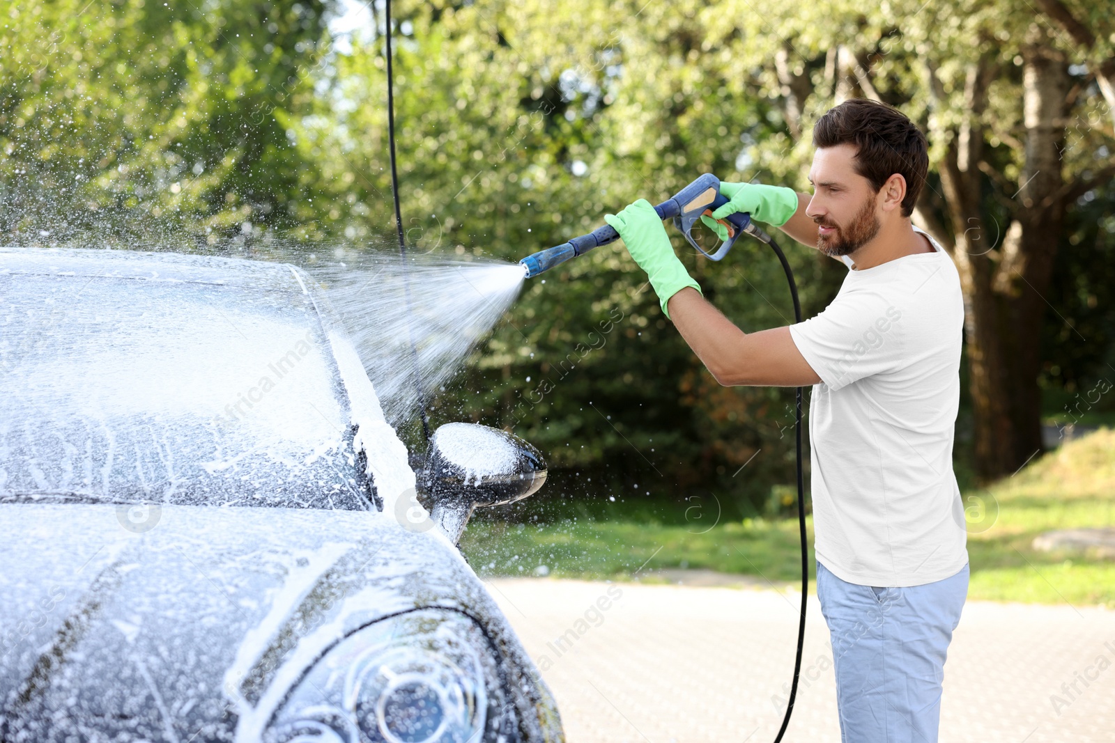 Photo of Man covering automobile with foam at outdoor car wash