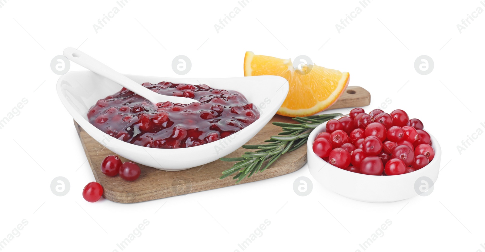 Photo of Tasty cranberry sauce in bowl, fresh berries, orange wedge and rosemary isolated on white