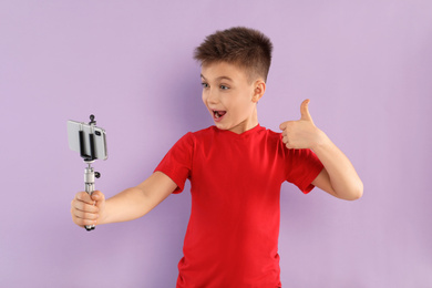 Excited little blogger recording video on violet background