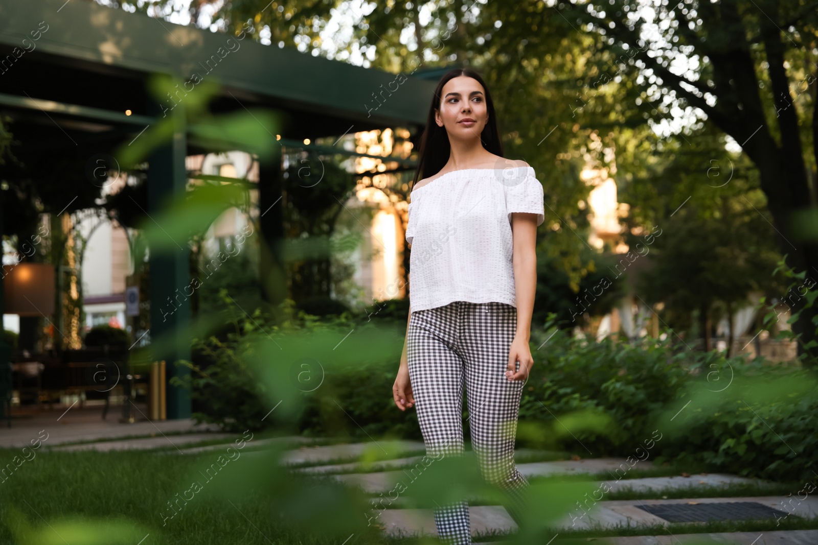 Photo of Beautiful young woman walking in green park, space for text