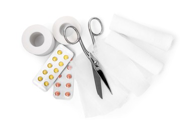 Medical bandage rolls, pills, sticking plaster and scissors on white background, top view