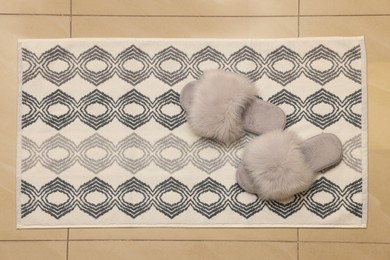 Soft bath mat and slippers on floor, top view