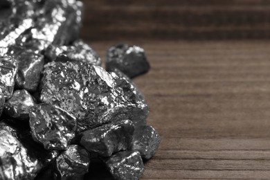 Photo of Pile of silver nuggets on wooden table, closeup. Space for text