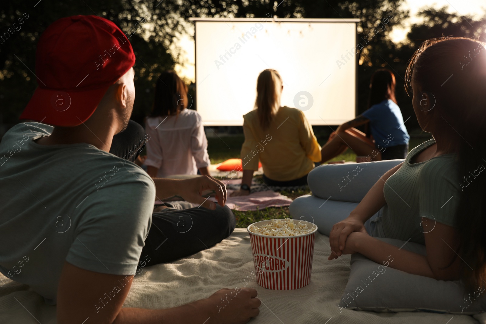 Photo of Young couple with popcorn watching movie in open air cinema. Space for text