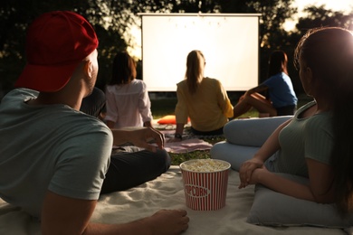 Young couple with popcorn watching movie in open air cinema. Space for text