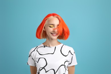 Beautiful young woman with bright dyed hair shaking head on turquoise background