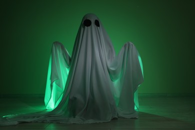 Creepy ghost. Woman covered with sheet in green light