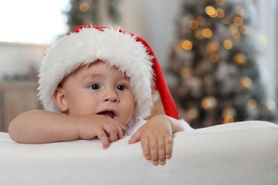 Image of Cute little baby wearing Santa hat at home. Christmas celebration