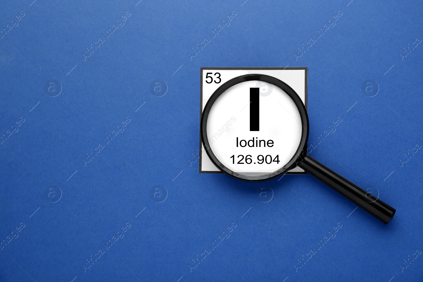 Photo of Card with iodine element and magnifying glass on blue background, flat lay. Space for text