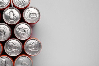 Photo of Energy drink in cans on grey background, top view. Space for text