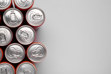 Energy drink in cans on grey background, top view. Space for text