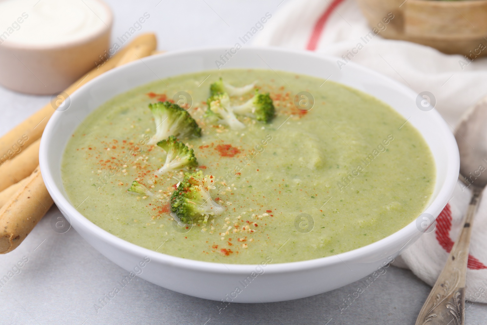 Photo of Delicious broccoli cream soup served on light table, closeup