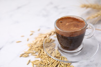 Photo of Cup of barley coffee, grains and spike on light table, closeup. Space for text