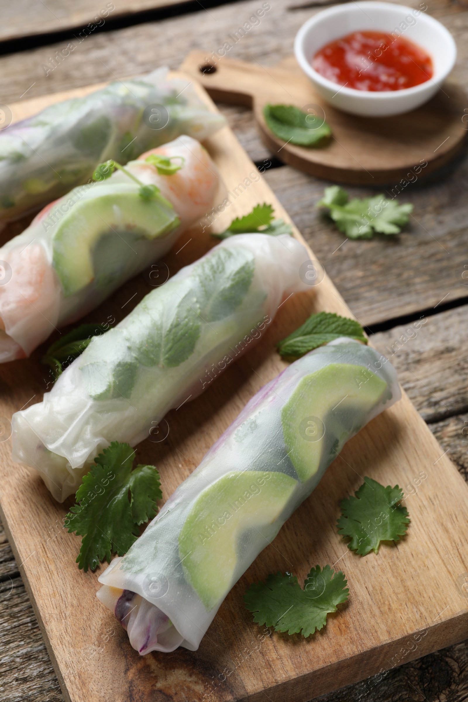 Photo of Delicious spring rolls and sauce on wooden table