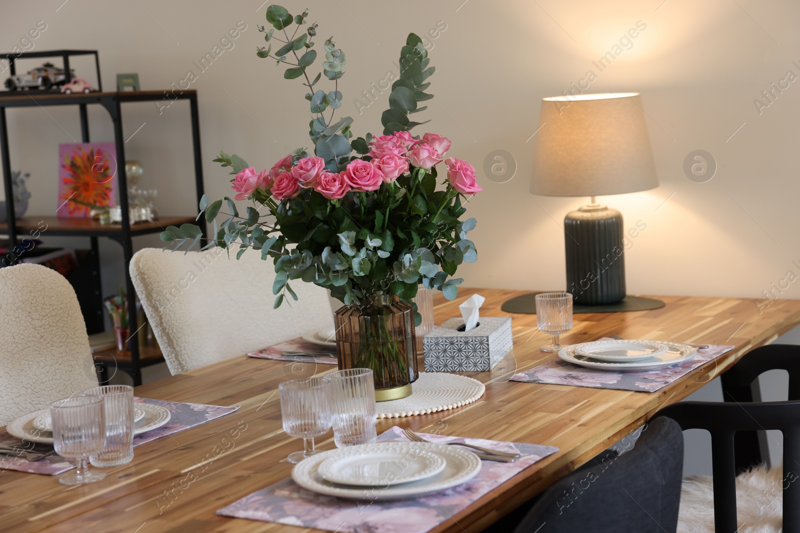 Photo of Beautiful table setting with bouquet indoors. Roses and eucalyptus branches in vase