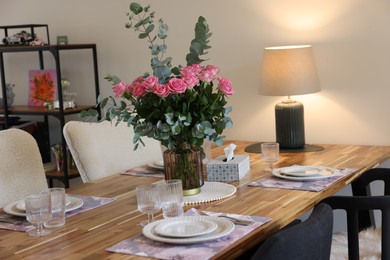 Beautiful table setting with bouquet indoors. Roses and eucalyptus branches in vase