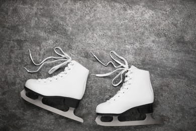 Pair of white ice skates on grey background, top view