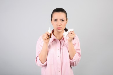Photo of Woman with nasal spray and tissues on light grey background