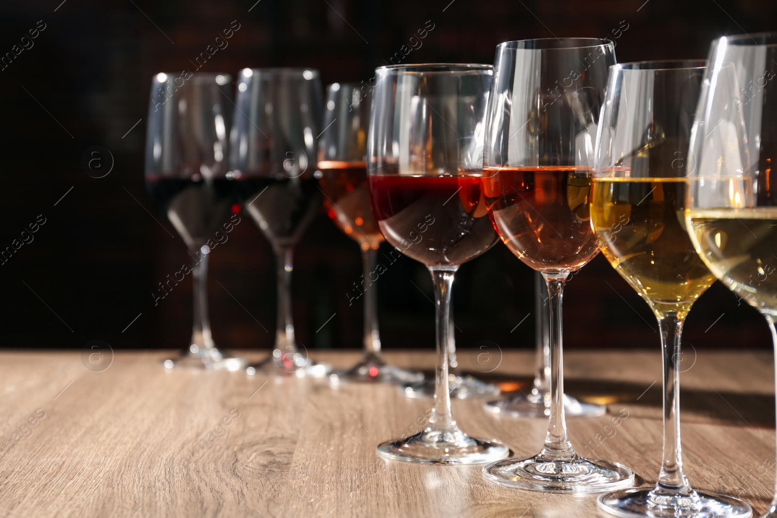 Photo of Different tasty wines in glasses on wooden table, space for text