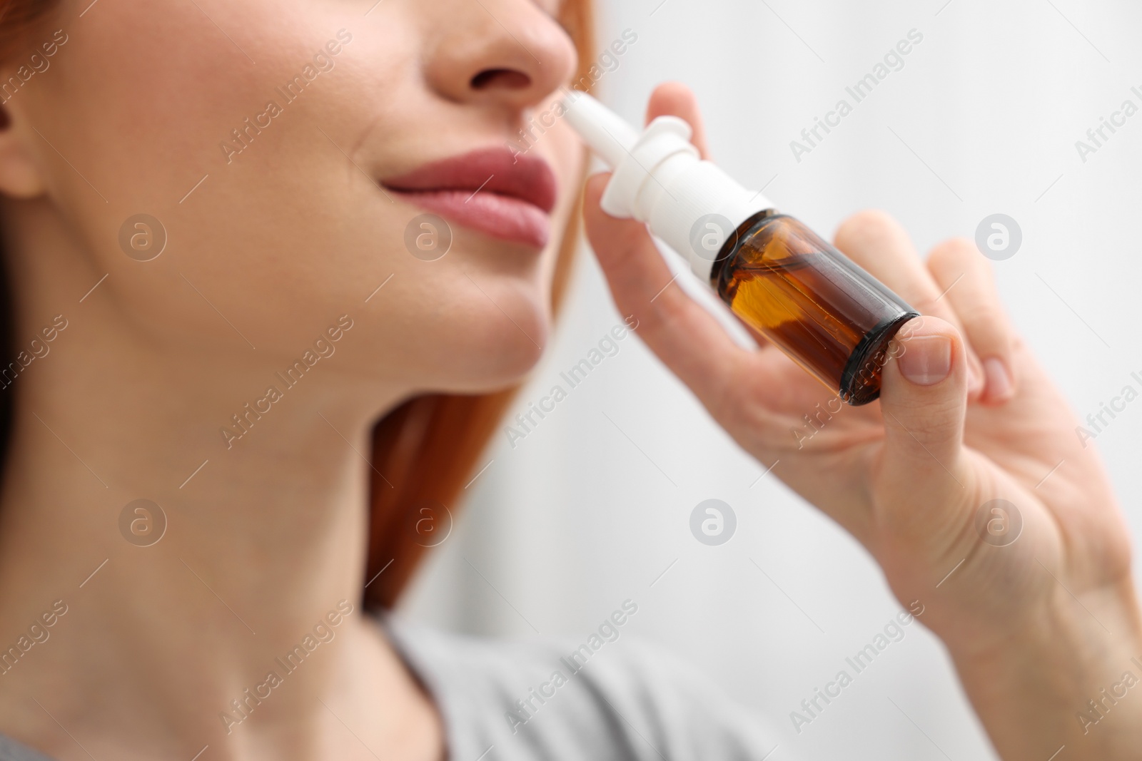 Photo of Medical drops. Woman using nasal spray at home, closeup