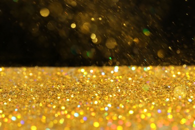 Many golden paillettes against black background. Space for text