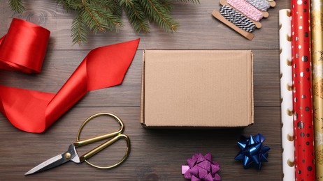 Photo of Box, wrapping paper and scissors on wooden table, flat lay