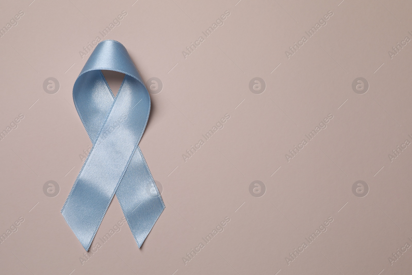 Photo of International Psoriasis Day. Light blue ribbon as symbol of support on beige background, top view. Space for text