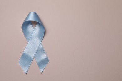 International Psoriasis Day. Light blue ribbon as symbol of support on beige background, top view. Space for text