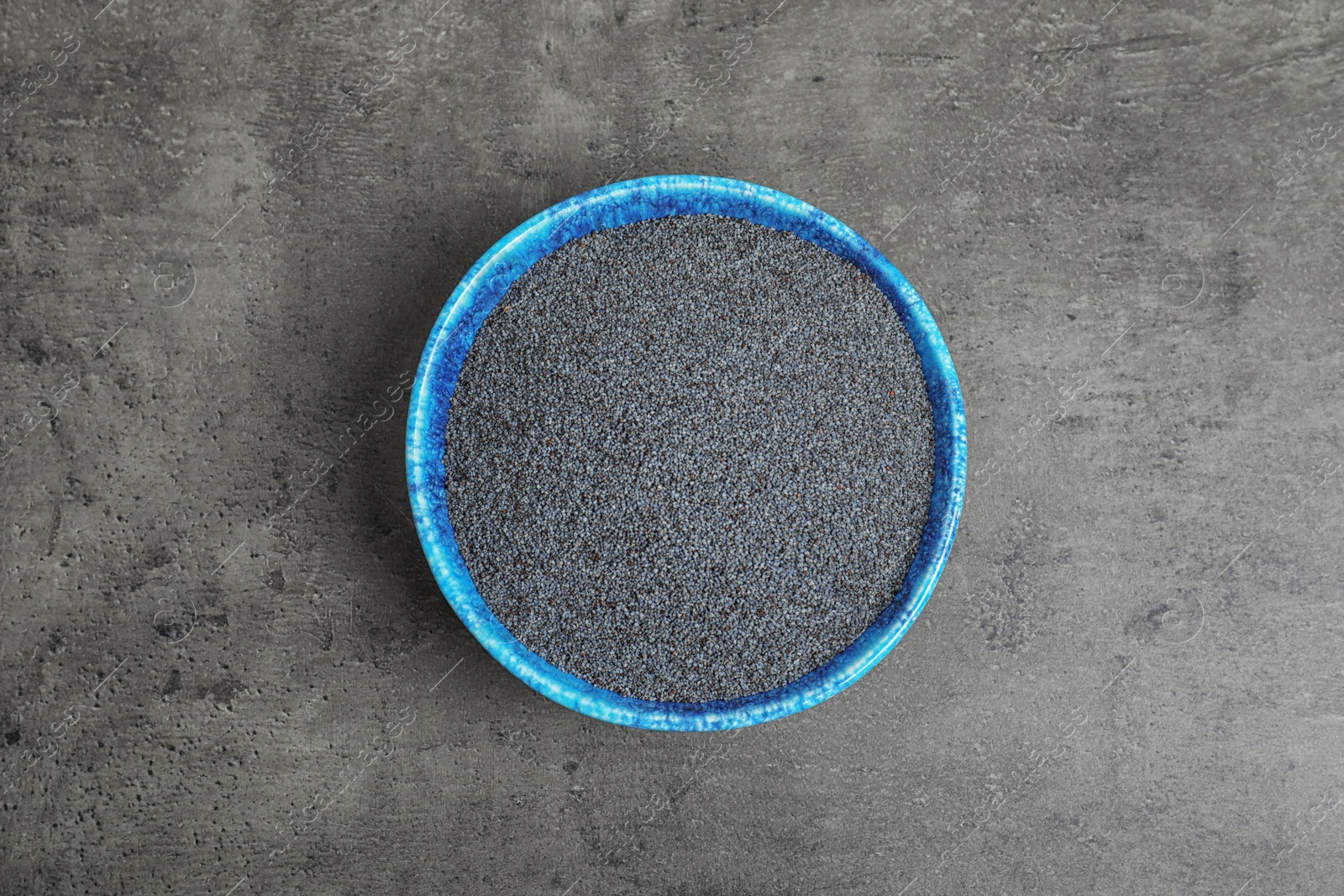 Photo of Poppy seeds in bowl on grey background, top view