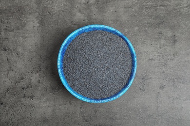 Poppy seeds in bowl on grey background, top view