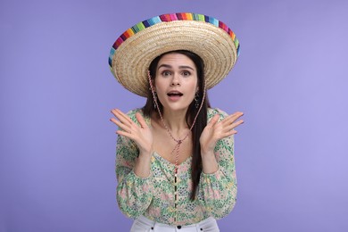 Surprised woman in Mexican sombrero hat on violet background