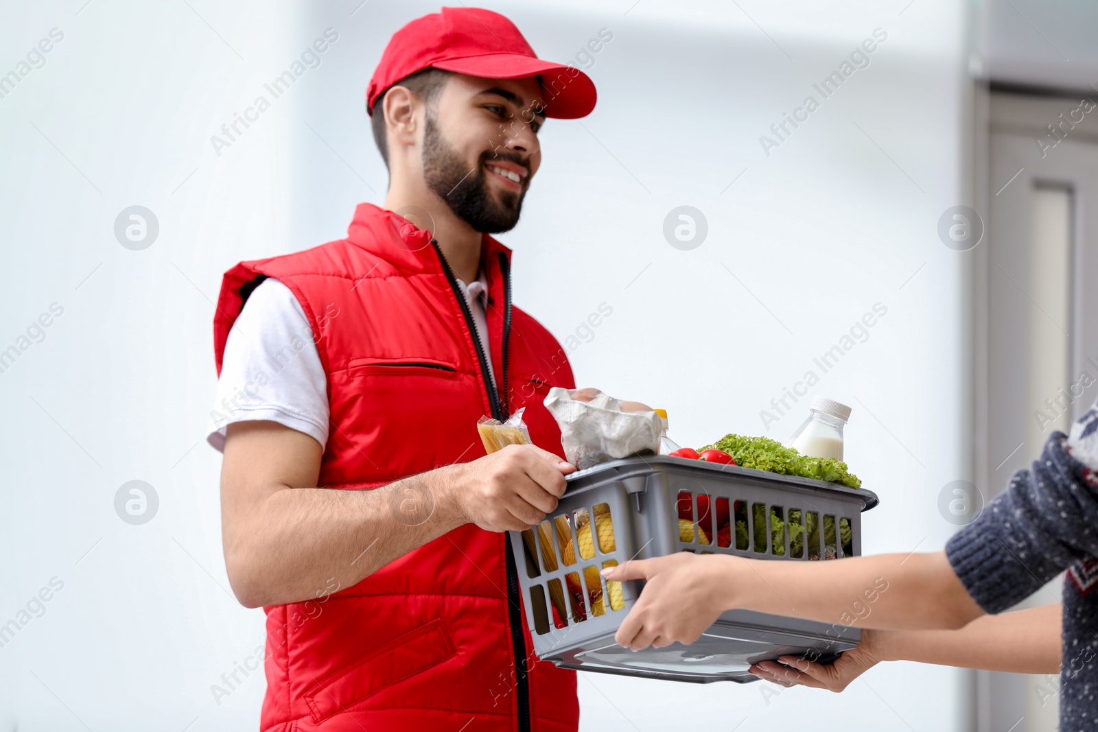 Photo of Young man delivering food to customer indoors