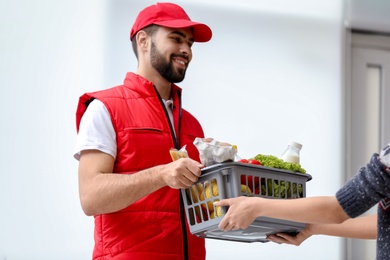 Photo of Young man delivering food to customer indoors